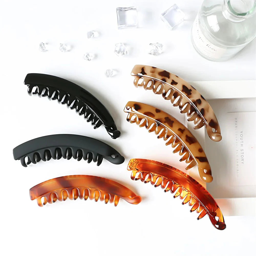 Frosted solid color banana hair clips by Clarivae, stylish ponytail barrettes and hair claws for women, shown in a close-up image.
